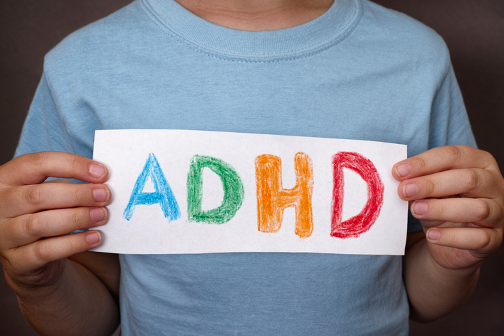 Poika pitelee kylttiä, jossa on värikäs ADHD-merkki.